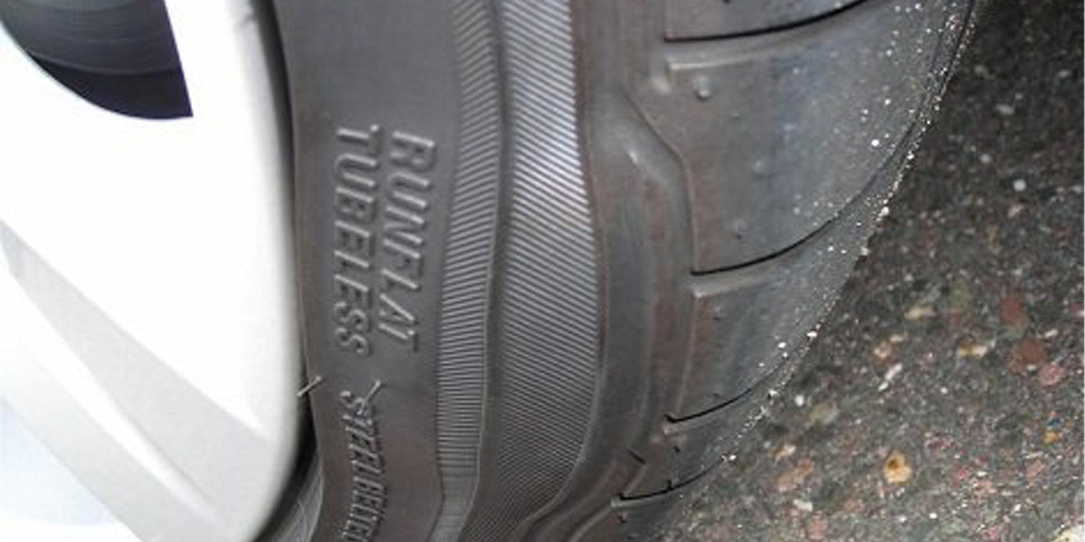 Lốp xe ô tô bị phồng với vết lồi rõ rệt trên thành lốp, minh họa nguy cơ nổ lốp.
